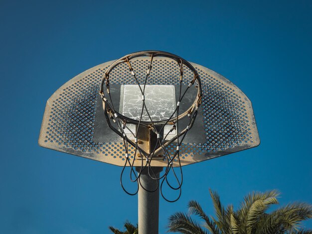 A low angle shot of a basketball hoop against a blue sunny sky