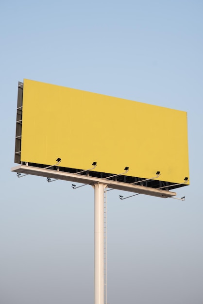 Low angle shot of a blank yellow billboard with copy space