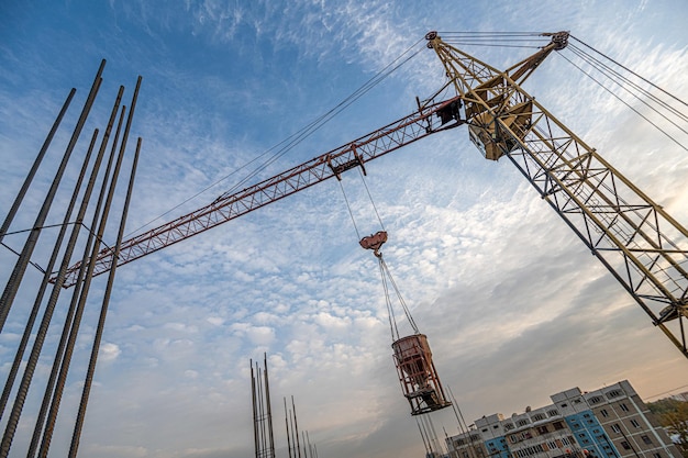 Un'inquadratura dal basso di una gru con attrezzatura in un cantiere edile vicino a una nuova infrastruttura edilizia