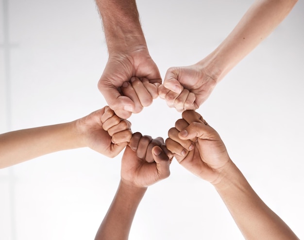 Low angle shot of a group of businesspeople joining their fists in solidarity