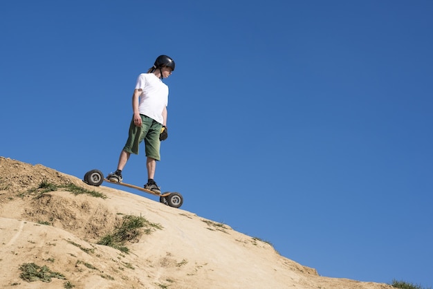 Low angle shot of a male mountainboarder on a hill slope