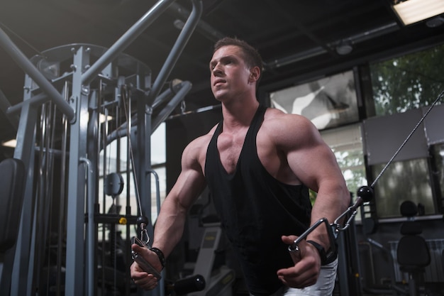 Low angle shot of a muscular sportsman exercising in cable crossover gym machine