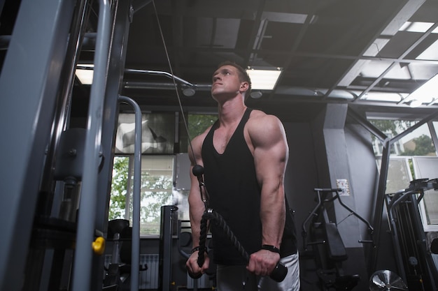 Low angle shot of a muscular sportsman training at gym doing triceps workout