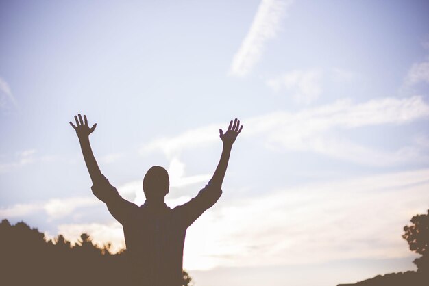 Photo low angle shot of a person with his hands up praying in nature - concept of faith in god