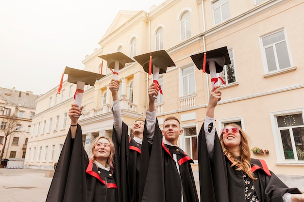 Low angle students holding diploma