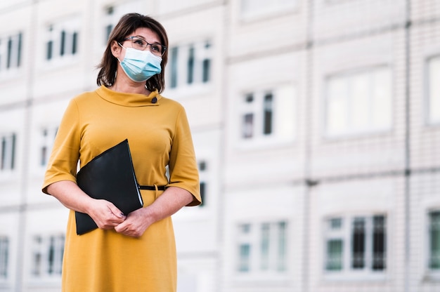 Foto insegnante di angolo basso con maschera all'aperto