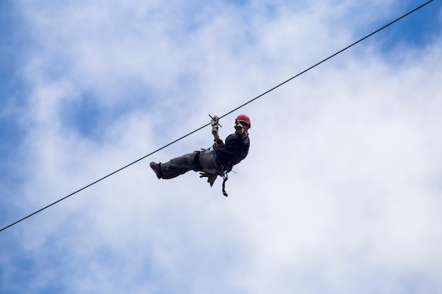 Low angle of tourist on zip line and gesturing against sky at costa rica