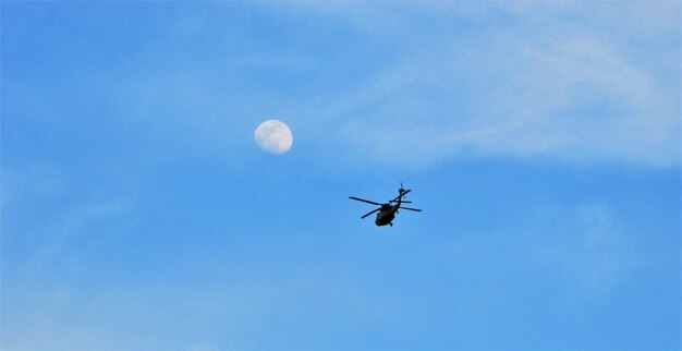 Low angle view of airplane in flight against blue sky