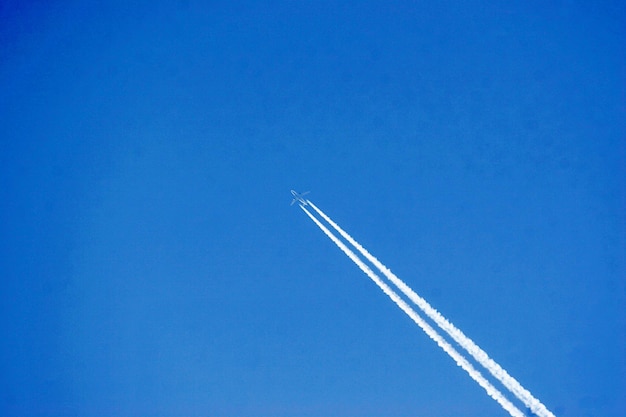 青い空に向かって飛ぶ飛行機の低角度の視点
