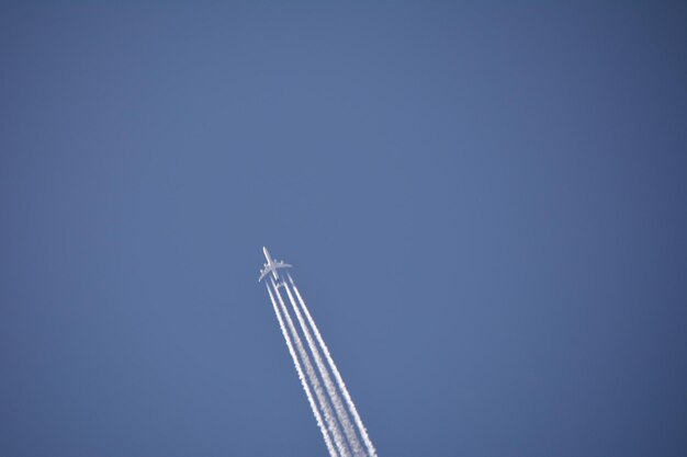 Low angle view of airplane flying against clear blue sky