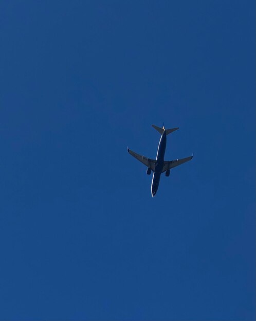 Low angle view of airplane flying against clear blue sky