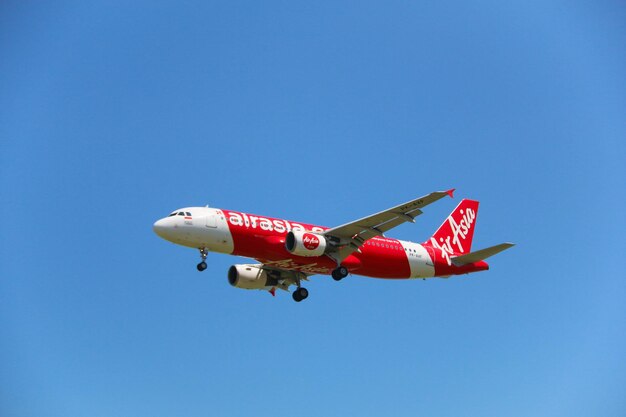 Low angle view of airplane flying against clear blue sky