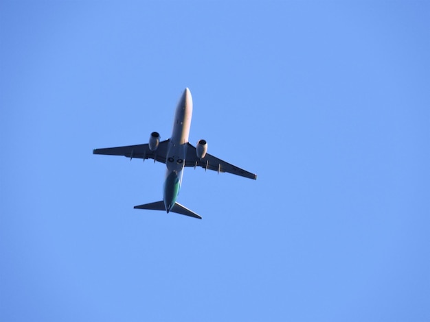 Low angle view of airplane flying against clear blue sky