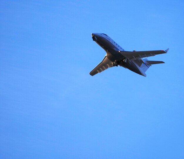 Low angle view of airplane flying against clear blue sky