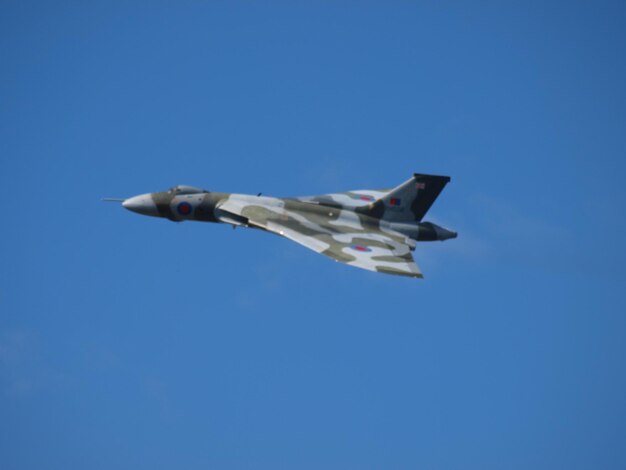 Low angle view of airplane flying against clear blue sky