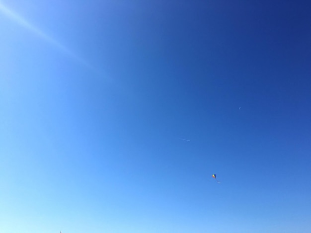 Low angle view of airplane flying against clear blue sky