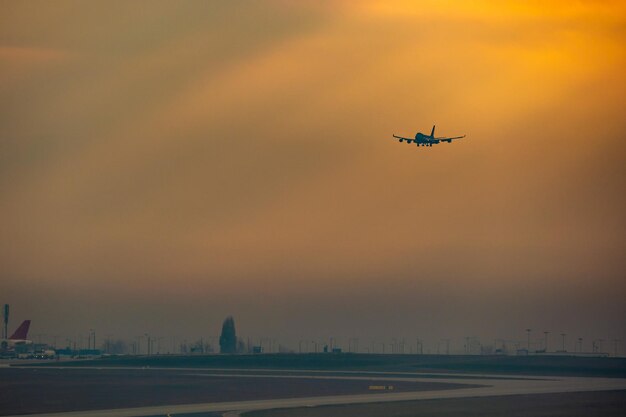 Low angle view of airplane flying in sky during sunset