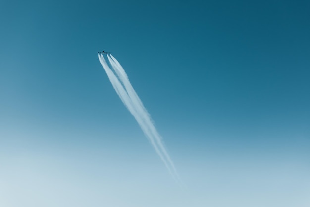 Foto vista a basso angolo di un aereo che vola con tracce di vapore in un cielo blu limpido