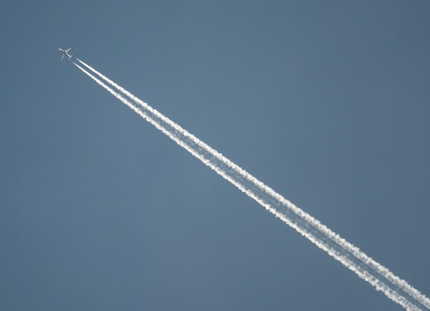 Foto vista a basso angolo dell'aereo che forma il processo di vapore contro un cielo limpido