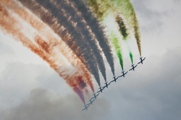 Foto vista a basso angolo di aerei che emettono tracce di vapore multicolori nel cielo