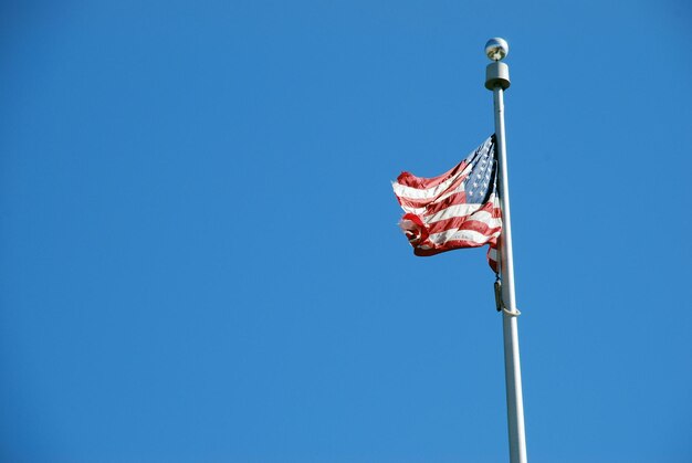 Photo low angle view of american flag against clear blue sky