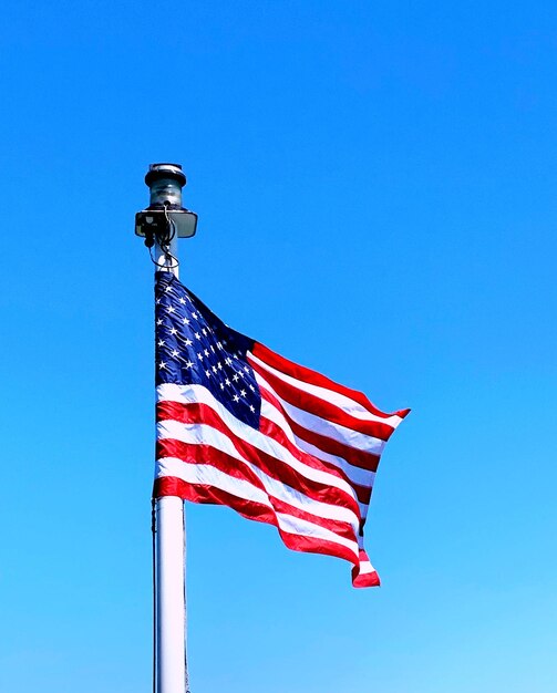 Low angle view of american flag against clear blue sky