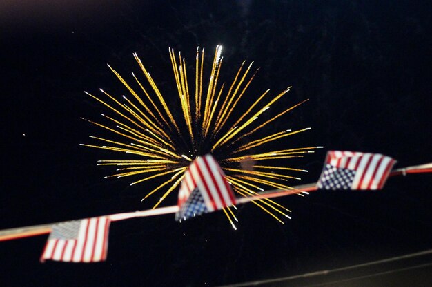 Photo low angle view of american flag buntings against firework display at night