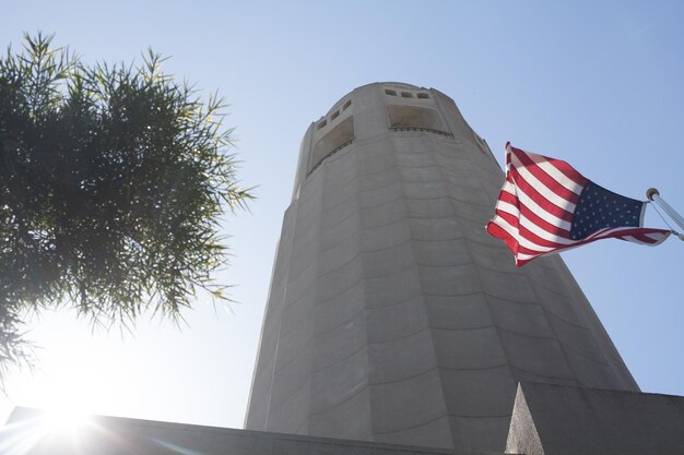 Photo low angle view of american flag and coit tower against clear sky