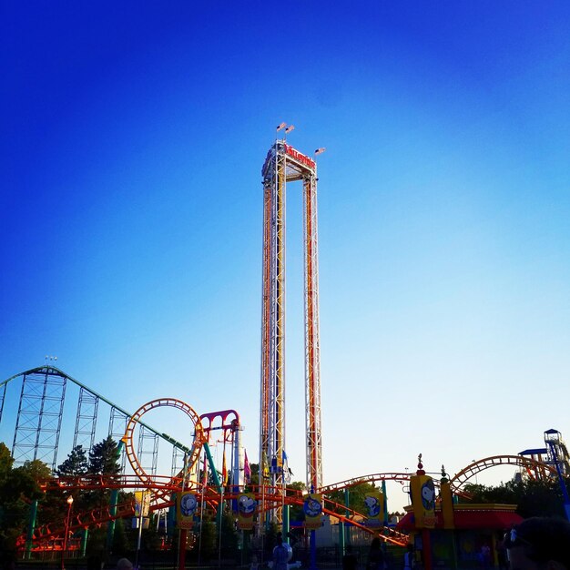 Photo low angle view of amusement park ride against blue sky