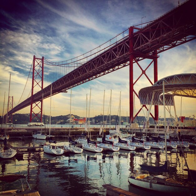 Photo low angle view of april 25th bridge over sailboats moored in river