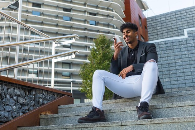 Low angle view of an Arab businessman sitting in outdoor stairs using phone