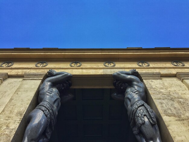 Vista a bassa angolazione delle statue dell'atlas al museo statale dell'ermitage contro un cielo blu limpido