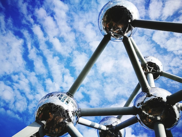 Low angle view of atomium against cloudy blue sky
