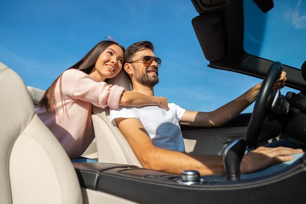 Photo low angle view of attractive woman and handsome man riding in convertible