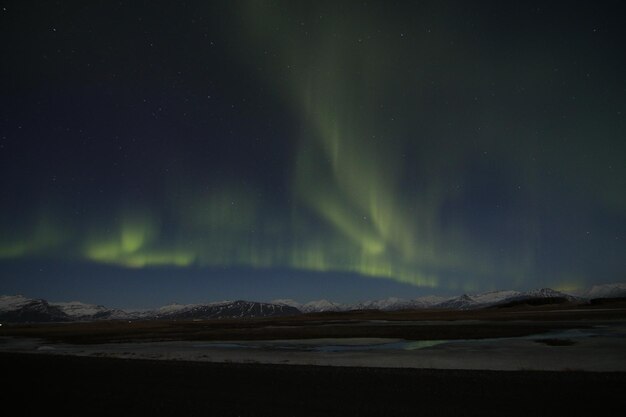 Photo low angle view of aurora borealis over mountains and lake