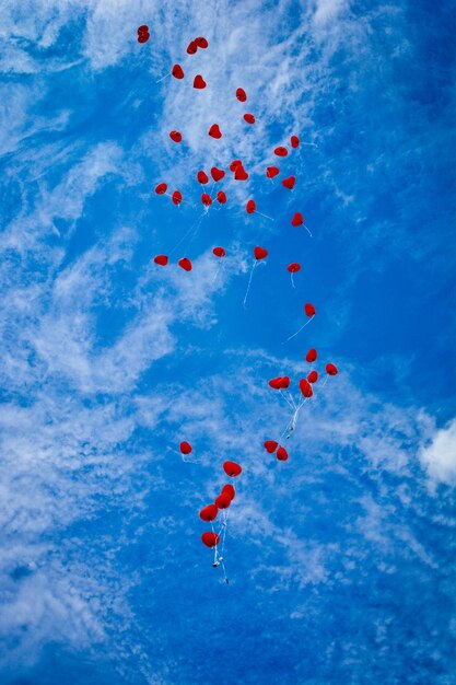 Low angle view of balloons flying against blue sky