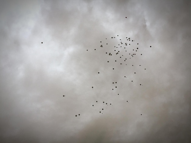 Low angle view of balloons flying against cloudy sky