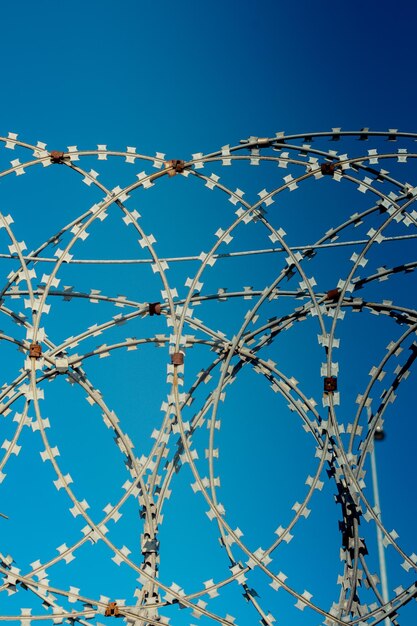 Low angle view of barbed wire against clear blue sky