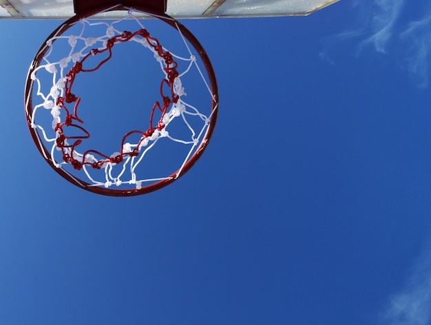 Foto vista a bassa angolazione del cerchio di basket contro il cielo blu