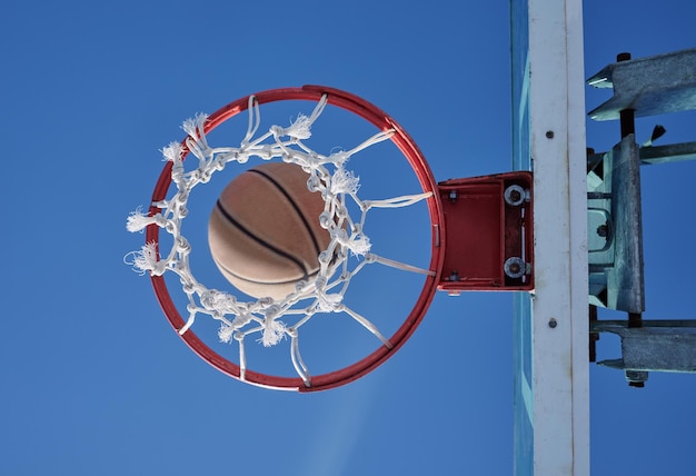 Foto vista a basso angolo del cerchio di basket contro un cielo blu limpido