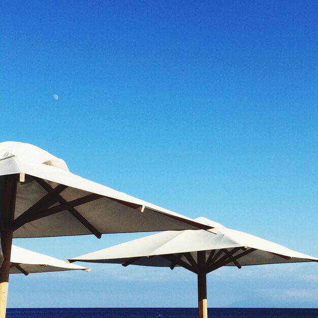 Low angle view of beach umbrella against clear blue sky