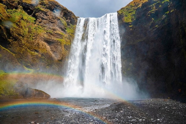 Vista ad angolo basso di bellissimi arcobaleni e cascata di skogafoss che cadono dalle scogliere