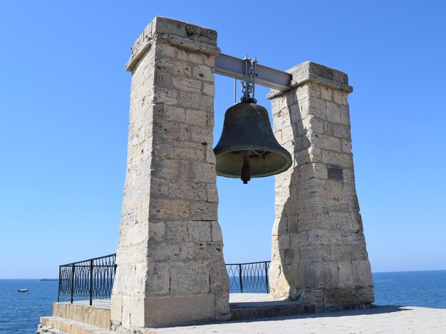 Low angle view of bell hanging against clear blue sky