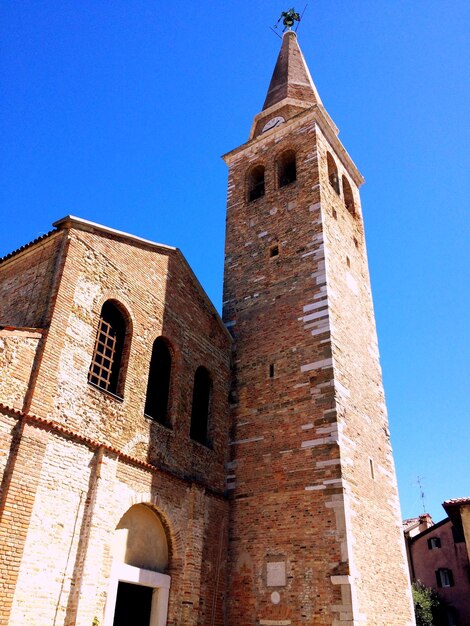 Low angle view of bell tower against clear blue sky