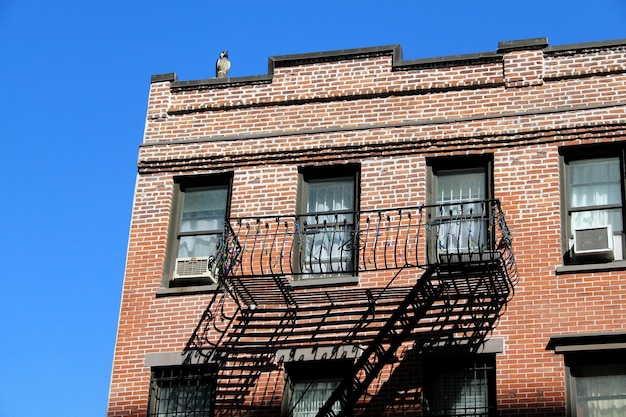 Photo low angle view of bird on brick wall building against clear sky