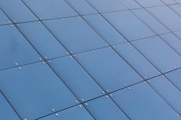 Vista di angolo basso della riflessione di vetro blu sulla facciata della costruzione