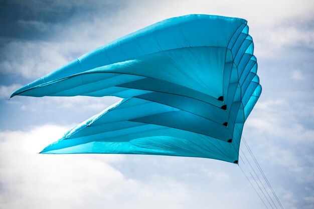 low angle view of blue kite flying against cloudy sky