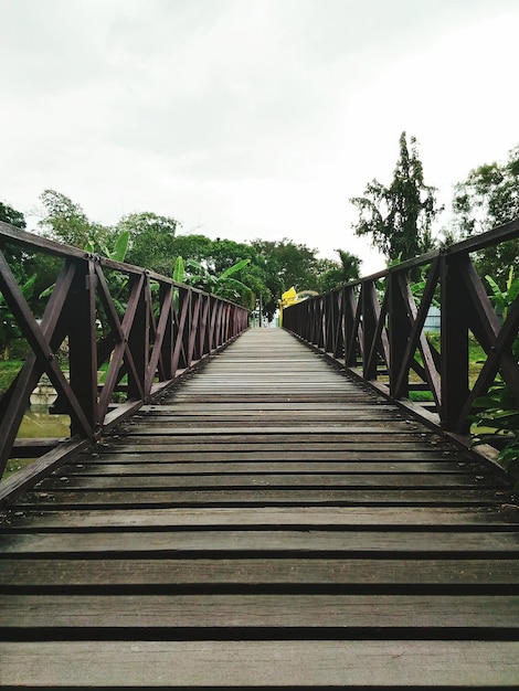 Low angle view of boardwalk at field against sky