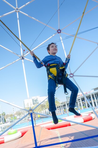 Foto vista a bassa angolazione di un ragazzo che salta bungee contro un cielo limpido