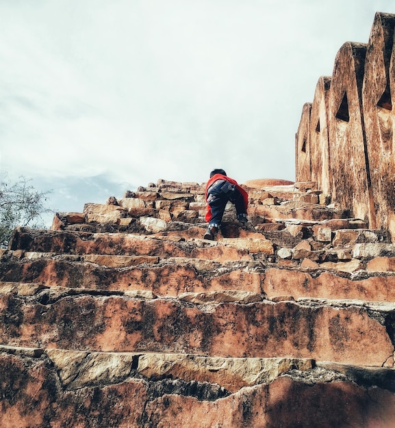 Low angle view of boy climbing staircase against sky